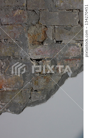 A layer of alabaster stucco has fallen off and revealing old brickwork. Clean empty space and ancient brick wall vertical stock photo 134270451