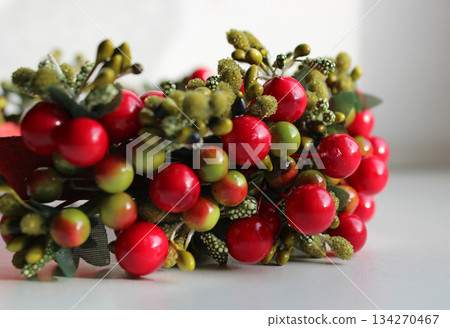 Part Of Wreath With Artificial Colored Berries And Textile Leaves On White Background Closeup Side View Part Of Wreath With Artificial Colored Berries And Textile Leaves On White Background Closeup Side View 134270467