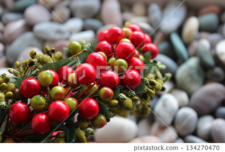 Decorative Wreath With Artificial Berries And Branches On Defocused Smooth Rocks Backdrop Decorative Wreath With Artificial Berries And Branches On Defocused Smooth Rocks Backdrop 134270470