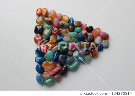 Triangle laid out from colored decorative stone crystals on a white surface Triangle laid out from colored decorative stone crystals on a white surface 134270514