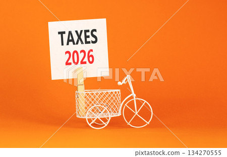 Taxes 2026 symbol. Concept words Taxes 2026 on beautiful white paper on wooden clothespin. Beautiful orange background. Beautiful miniature bicycle. Business taxes 2026 new year concept. Copy space. 134270555