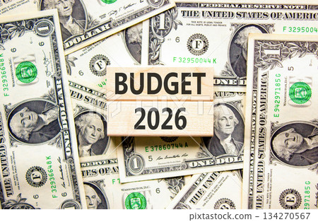 Budget 2026 symbol. Concept words Budget 2026 on beautiful wooden blocks. Beautiful dollar bills background. Dollar bills. Business and budget 2026 concept. Copy space. Budget 2026 symbol. Concept words Budget 2026 on beautiful wooden blocks. Beautiful dollar bills background. Dollar bills. Business and budget 2026 concept. Copy space. 134270567