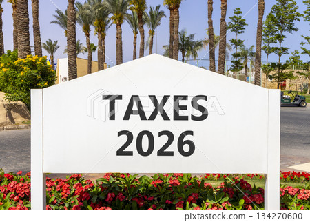 Taxes 2026 new year symbol. Concept words Taxes 2026 on beautiful white road sign. Beautiful palm trees palm-trees and blue sky background. Business and taxes 2026 new year concept. Copy space. 134270600
