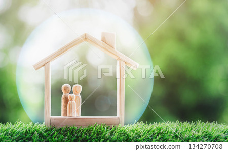 Wooden home with happy family of wooden doll is placed inside on nature bokeh. The saving money for house or real estate owner in the future concept. 134270708