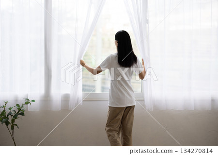 身穿白大褂的女子背對著鏡頭拉開窗簾 134270814