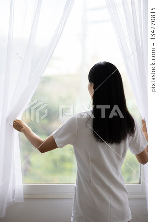 身穿白大褂的女子背對著鏡頭拉開窗簾 134270815