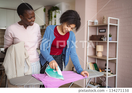 Mother and Daughter Ironing Clothes Together at Home 134271138