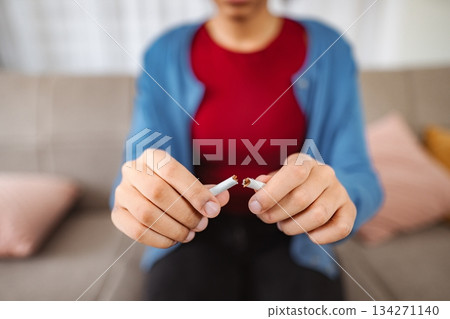 Woman breaking cigarette and quitting smoking at home 134271140