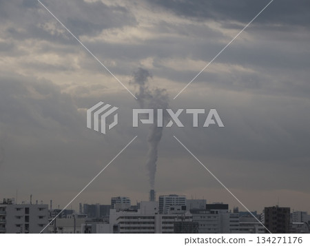 Cityscape under a cloudy sky: factory chimneys emitting tall white smoke and a densely packed residential area Cityscape under a cloudy sky: factory chimneys emitting tall white smoke and a densely packed residential area 134271176