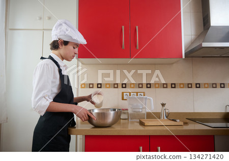 Young Chef In White Uniform Preparing Batter In A Red Modern Studio Kitchen At Home 134271420