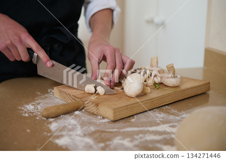 Chef Slices Mushrooms On Wooden Cutting Board For Fresh Home Cooking Chef Slices Mushrooms On Wooden Cutting Board For Fresh Home Cooking 134271446