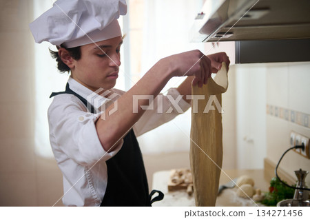 Young Chef Makes Flat Dough Sheet In Bright Kitchen, Focusing On Culinary Craft Young Chef Makes Flat Dough Sheet In Bright Kitchen, Focusing On Culinary Craft 134271456