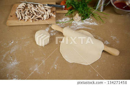Fresh Dumpling Dough Rolling On Kitchen Table with Mushrooms, Herbs, and Flour Fresh Dumpling Dough Rolling On Kitchen Table with Mushrooms, Herbs, and Flour 134271458