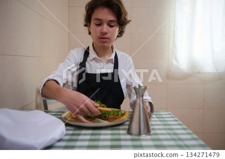 Young Chef in White Shirt and Black Apron Preparing Fresh Pizza 134271479