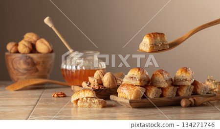 Baklava with walnuts and honey on a beige background. Baklava with walnuts and honey on a beige background. 134271746