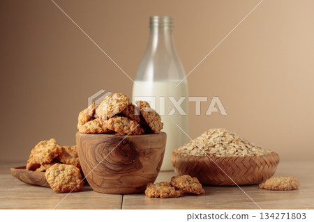 Oatmeal cookies and milk sit on a kitchen table. 134271803