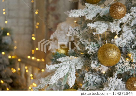 Snowy Christmas tree with shining golden ball. Winter holiday decoration. New year celebration background for copy space. Snowy Christmas tree with shining golden ball. Winter holiday decoration. New year celebration background for copy space. 134271844