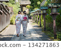 Two young women in yukata robes walking beside wooden lanterns on the approach to a shrine. Kyoto City, Kyoto Prefecture, Japan 134271863
