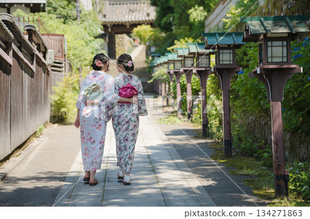 兩名身著浴衣的年輕女子,手持木製燈籠,走在通往神社的路上。日本京都府京都市 兩名身著浴衣的年輕女子,手持木製燈籠,走在通往神社的路上。日本京都府京都市 134271863