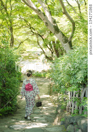 一位身著浴衣、手提竹籃的女子漫步在靜謐庭院的石板路上。日本京都府京都市 134271868