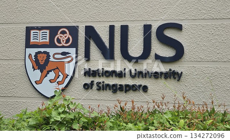 The NUS emblem with lion, rings, and book stands proudly on a stone wall, symbolizing strength, unity The NUS emblem with lion, rings, and book stands proudly on a stone wall, symbolizing strength, unity 134272096