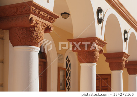 Intricate stone columns support a sunlit architectural structure in a warm-toned building during day Intricate stone columns support a sunlit architectural structure in a warm-toned building during day 134272166