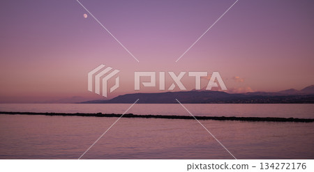 Soft purple horizon with calm reflective water and dark breakwater line Soft purple horizon with calm reflective water and dark breakwater line 134272176