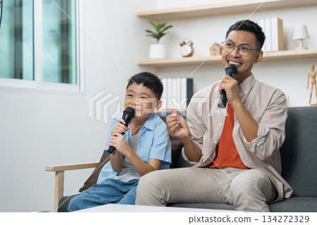 Father and son singing together with microphones at home Father and son singing together with microphones at home 134272329