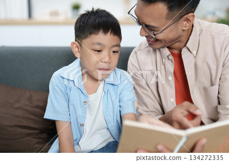 Learning Together. Father reading a book with his son, fostering education and connection. Learning Together. Father reading a book with his son, fostering education and connection. 134272335