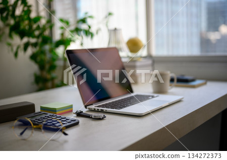 在靠窗明亮的辦公桌前準備工作:筆記型電腦和文具 在靠窗明亮的辦公桌前準備工作:筆記型電腦和文具 134272373