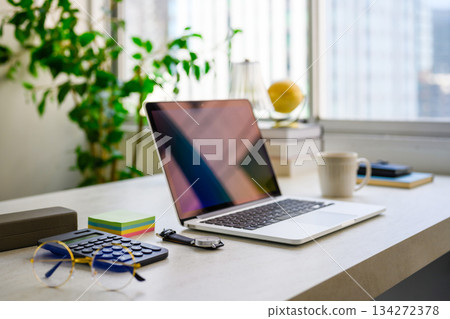 A bright office desk and a table by the window that lets in natural light 134272378
