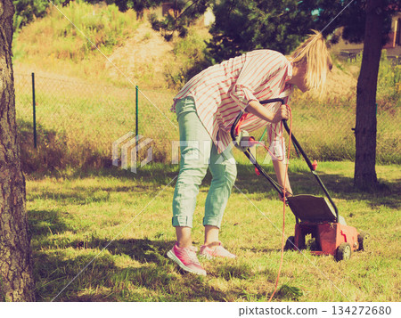 Woman mowing green grass Woman mowing green grass 134272680