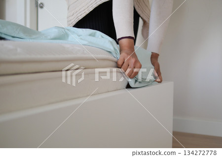 Person putting on a light blue bed cover in a bedroom 134272778