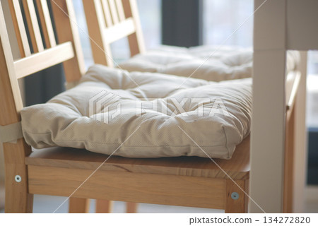 Padded cushions on wooden chairs indoors near a window 134272820