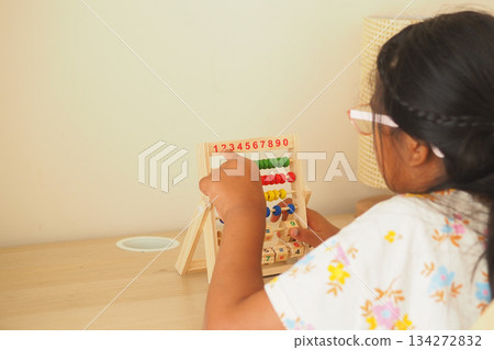 Child plays with counting beads at a table in the room 134272832
