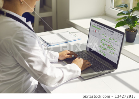 Doctor using laptop calendar to manage appointments in modern clinic office Doctor using laptop calendar to manage appointments in modern clinic office 134272913