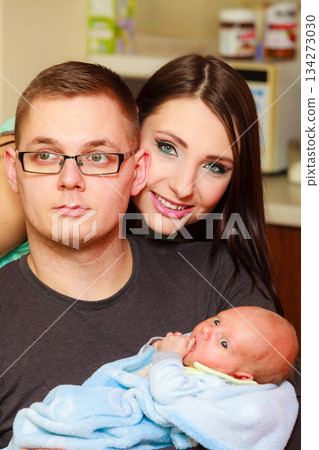 Father holding baby, mother standing behind them. 134273030