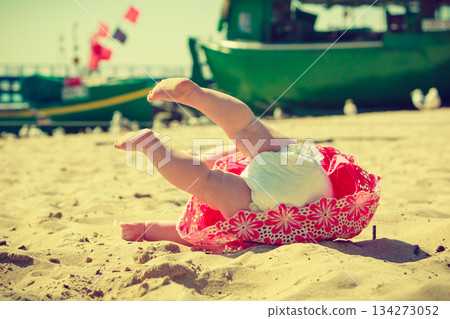 Small child fell over on the sand. 134273052