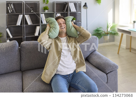 Stressed tenant blocking noise with cushions during neighbor disturbance at home Stressed tenant blocking noise with cushions during neighbor disturbance at home 134273068