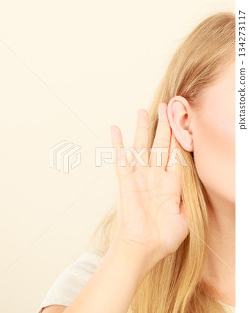 Woman putting hand ear to hear better Woman putting hand ear to hear better 134273117