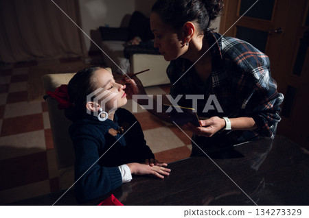Mother Applies Makeup To Daughter At Home For A Cute Family Moment 134273329