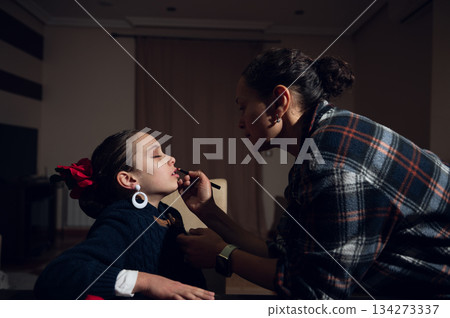 Mother Applies Lipstick To Daughter In Cozy Home Setting During Quiet Beauty Moment 134273337