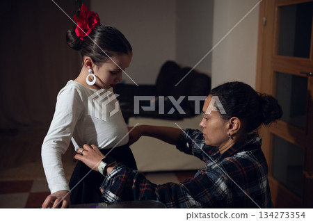 Mother Helps Pregnant Daughter Dress At Home During Tender Family Moment For Photo Shoot 134273354