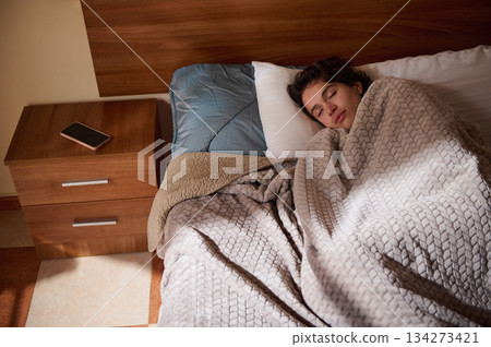 Cozy Sleep Scene Of Person Resting In Bed Under Blanket With Phone On Nightstand Cozy Sleep Scene Of Person Resting In Bed Under Blanket With Phone On Nightstand 134273421