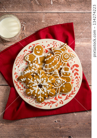 Holiday background. Christmas gingerbread cookies in a plate with glass of milk, festive food, home baking. Flat lay 134274223