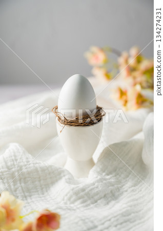 Easter spring background. Egg in a ceramic egg holder stand with flowers. Minimalistic Easter spring background. Egg in a ceramic egg holder stand with flowers. Minimalistic 134274231