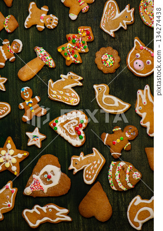 Assorted gingerbread shapes rest on distressed wooden planks. Bright icing details create cheerful holiday accents. Assorted gingerbread shapes rest on distressed wooden planks. Bright icing details create cheerful holiday accents. 134274438