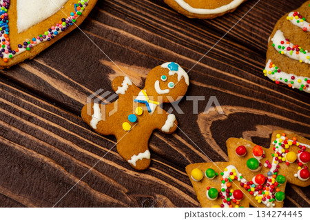 Gingerbread man figure on wooden background. Gingerbread character with icing accents lies centered on rustic wood Gingerbread man figure on wooden background. Gingerbread character with icing accents lies centered on rustic wood 134274445