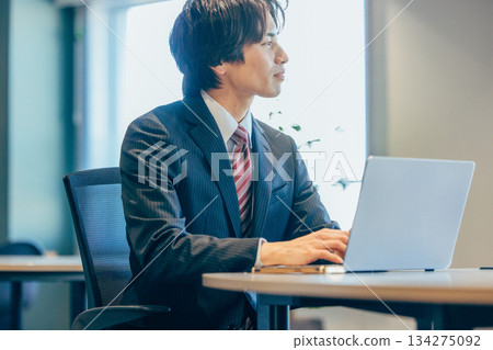 Businessman thinking while looking at a computer in the office 134275092