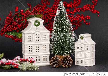 Ceramic Christmas houses with pine Tree and winter decorations on black textured background Ceramic Christmas houses with pine Tree and winter decorations on black textured background 134275137